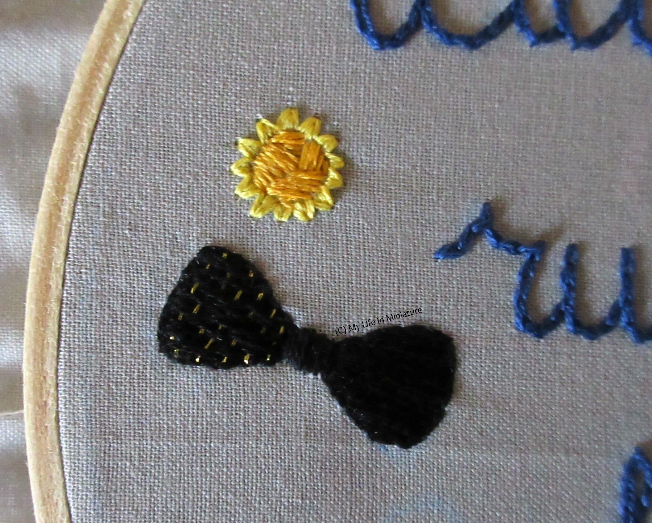A close-up of the yellow stitching from the last image, this time with the centre filled. It's filled with asymmetrical stitches in a darker yellow, and the motif looks like a daffodil head from straight-on. 