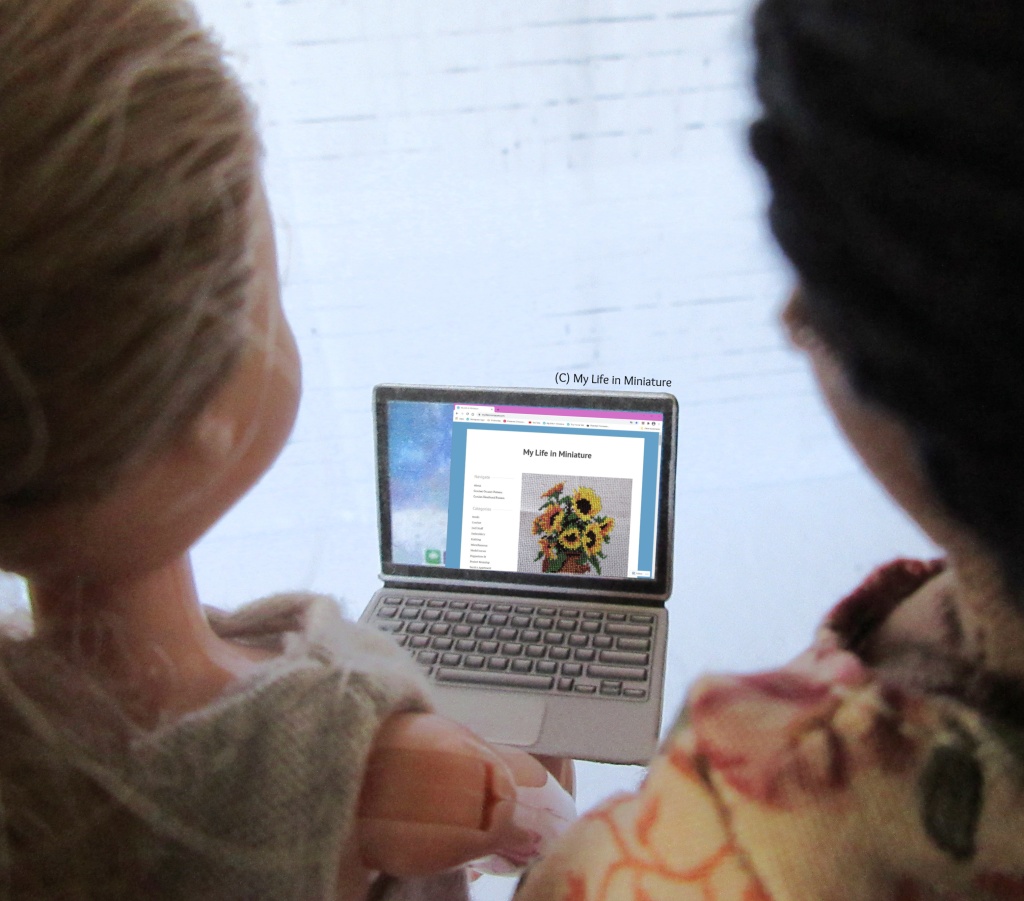 A view over the shoulders of Petra and Sarah of the laptop screen. On the screen, the homepage for My Life in Miniature is visible, showing the previous post. 
