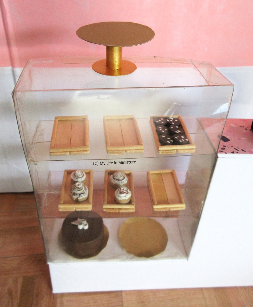 Close-up of the display case, photographed from above. The cake stand, wooden trays, and plates are easier to see. 