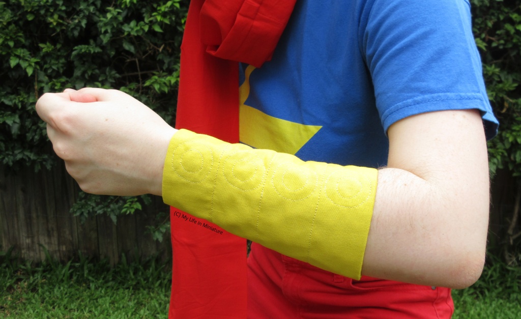 Closeup of the yellow fabric armband/gauntlet. It goes from the author's wrist to about her elbow crease, and is quilted with lines and concentric circles. 